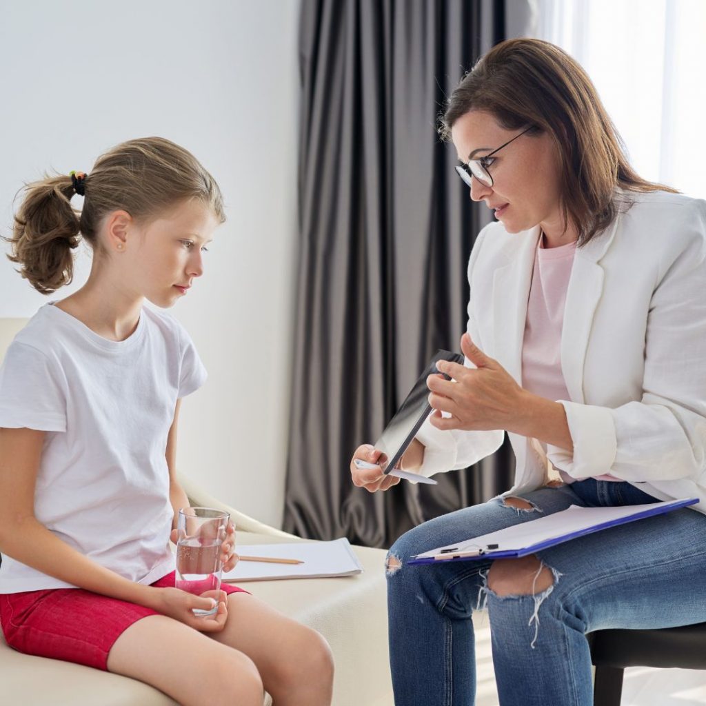 a child talking with a psychologist who is holding a tablet